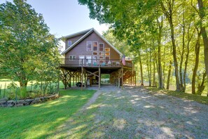 A wooden house with a covered porch, surrounded by trees. - Riverfront West Virginia Cabin w/ Screened-In Deck (Buckeye)