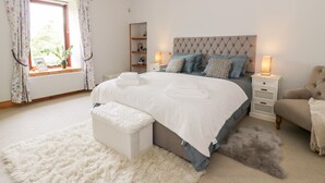 A bedroom with a large bed, bedside tables, a chair, and a window with curtains. - Shieldhill Farm House (Falkirk)
