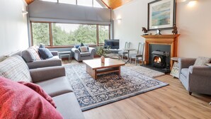A modern living room with a fireplace, large windows, and a cozy seating area. - Shieldhill Farm House (Falkirk)
