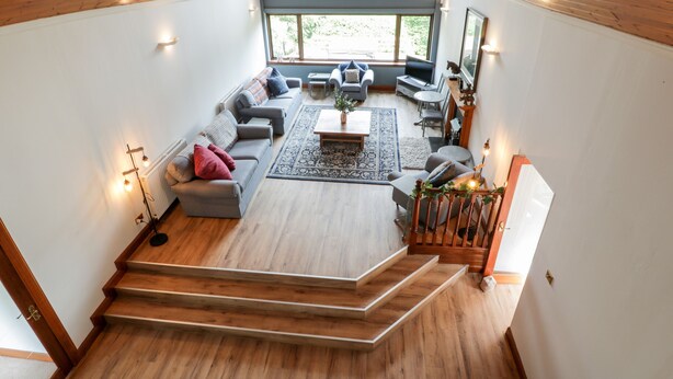 A spacious living area with a large window, a staircase, and a cozy seating arrangement. - Shieldhill Farm House (Falkirk)