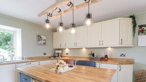 A modern kitchen with a wooden island, white cabinets, and pendant lighting. - Shieldhill Farm House (Falkirk)