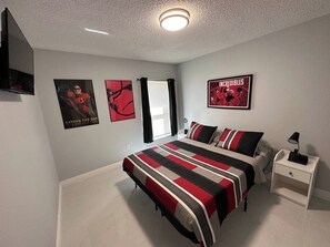 A bedroom with a bed, a nightstand, and posters on the wall.