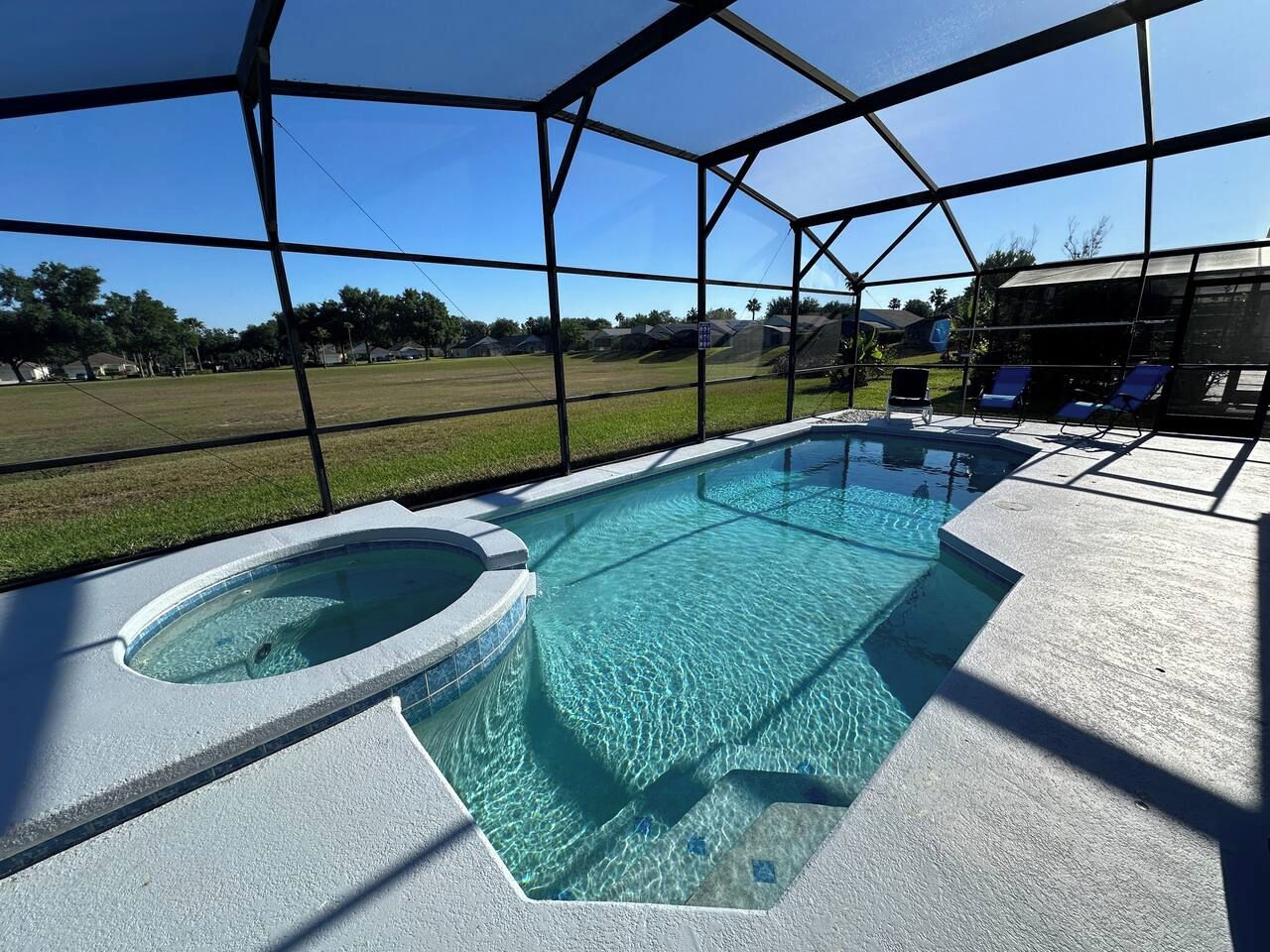 A swimming pool with a hot tub, surrounded by a covered area with lounge chairs.
