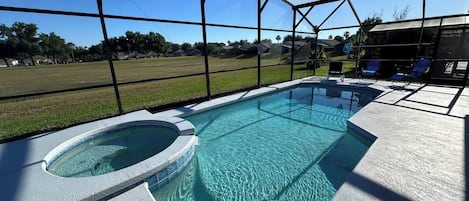 A swimming pool with a hot tub, surrounded by a covered area with lounge chairs.