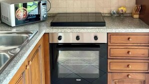 A kitchen with wooden cabinets, a microwave, a stove, and a sink.