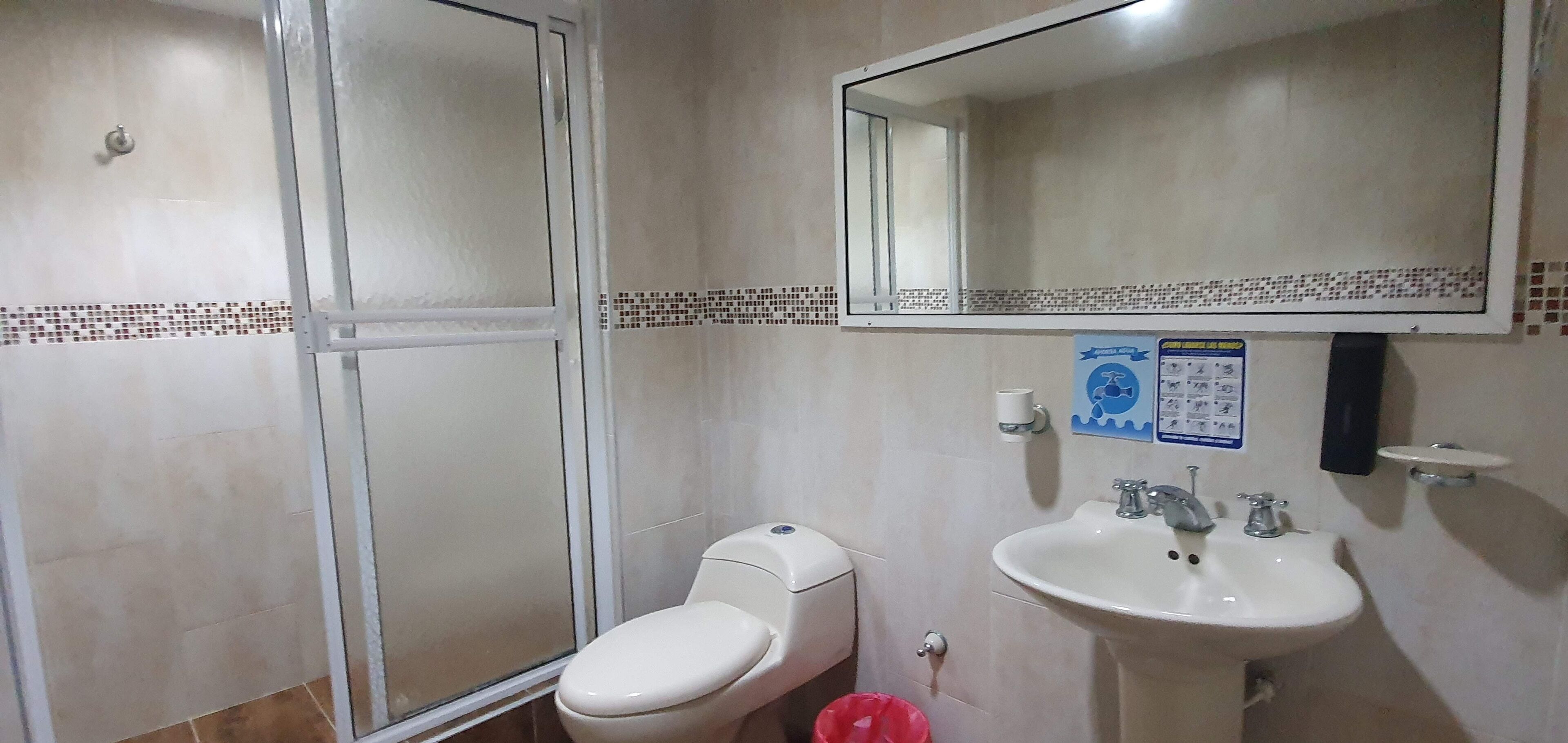 A bathroom with a toilet, sink, and shower.