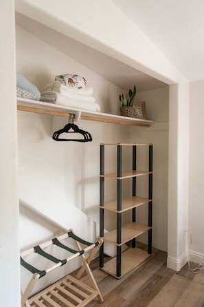 Storage area with a shelf unit and hanging rack, featuring a small potted plant.
