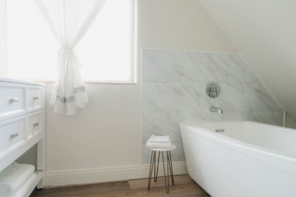 Ein modernes Badezimmer mit einer freistehenden Badewanne, einem Waschtisch mit Schubladen und einem kleinen Hocker.