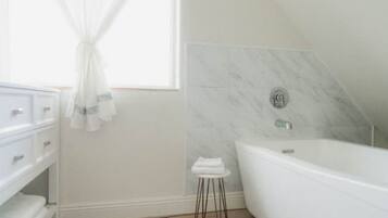 Ein modernes Badezimmer mit einer freistehenden Badewanne, einem Waschtisch mit Schubladen und einem kleinen Hocker.