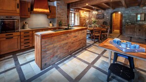 Une cuisine rustique avec des meubles en bois, un îlot central en briques et un mur en pierre.