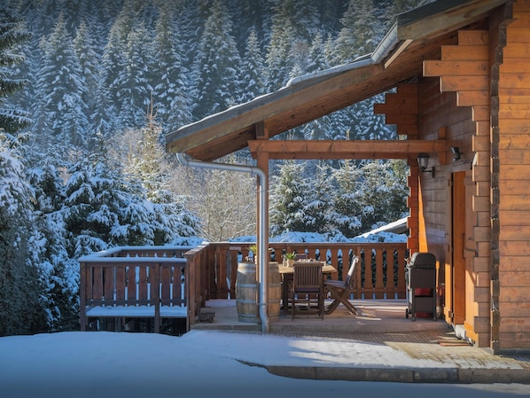 Une cabane en bois dotée d’un porche abrité, d’un banc et d’une table.