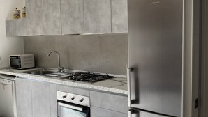 Una cocina moderna con armarios grises, un refrigerador de acero inoxidable, horno empotrado y microondas.