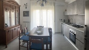 Una cocina moderna con comedor, que incluye un armario de madera, una lámpara de araña y una estufa empotrada.