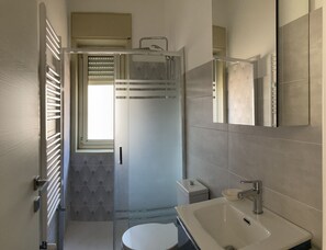Un baño moderno con cabina de ducha de vidrio, un inodoro y un lavabo con espejo.