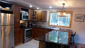 A modern kitchen with stainless steel appliances, wooden cabinets, and a glass island counter.