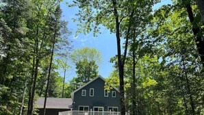 A two-story house with a balcony, surrounded by trees.