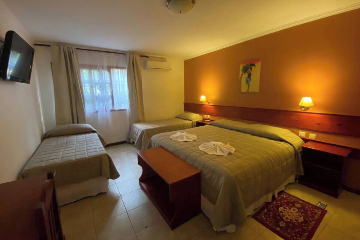 Ein Hotelzimmer mit zwei Einzelbetten, einer Couch, einem Schreibtisch und einem Fernseher.