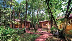 A pathway leading to a building surrounded by trees and greenery. - El Leñador (Puerto Iguazú)