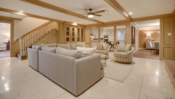 A spacious living room with a large sectional sofa, a chair, and a staircase. - Poolside Oasis Near Medical Center & NRG Stadium! (Houston)