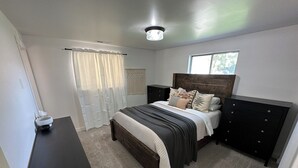 A bedroom with a bed, a dresser, a nightstand, a window, and a ceiling light. - Heart of Richfield, ATVs & Mountain Biking, Spacious Home, Sporting Events (Richfield)
