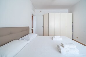 A hotel room with a bed, a wardrobe, and a nightstand.