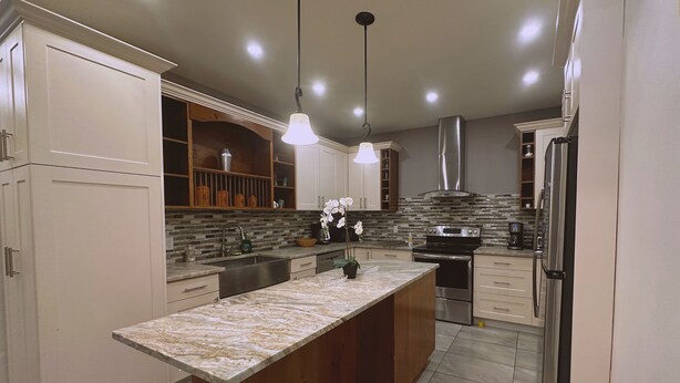 Una cocina moderna con una isla central, iluminación colgante y armarios empotrados.