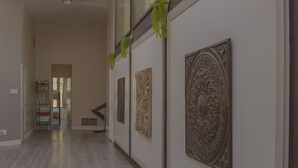 Un pasillo con piso de madera, un escurridor de metal con toallas dobladas y paneles decorativos en la pared.