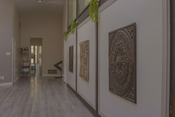 A hallway with a wooden floor, a metal rack with folded towels, and decorative wall panels.