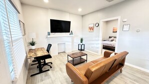 Ein modernes Wohnzimmer mit Kamin, Fernseher und Essbereich mit Tisch und Stühlen.