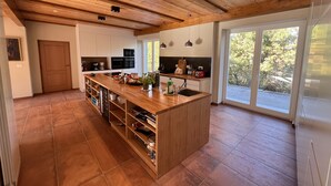 A spacious kitchen with a central island, wooden ceiling, and large windows offering a view of the outdoors. - GROUP STAY 39 GUESTS - POOL TENNISCOURT (Liguria)