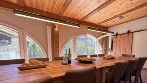A dining area with a long wooden table, several chairs, and a view of greenery through arched windows. - GROUP STAY 39 GUESTS - POOL TENNISCOURT (Liguria)