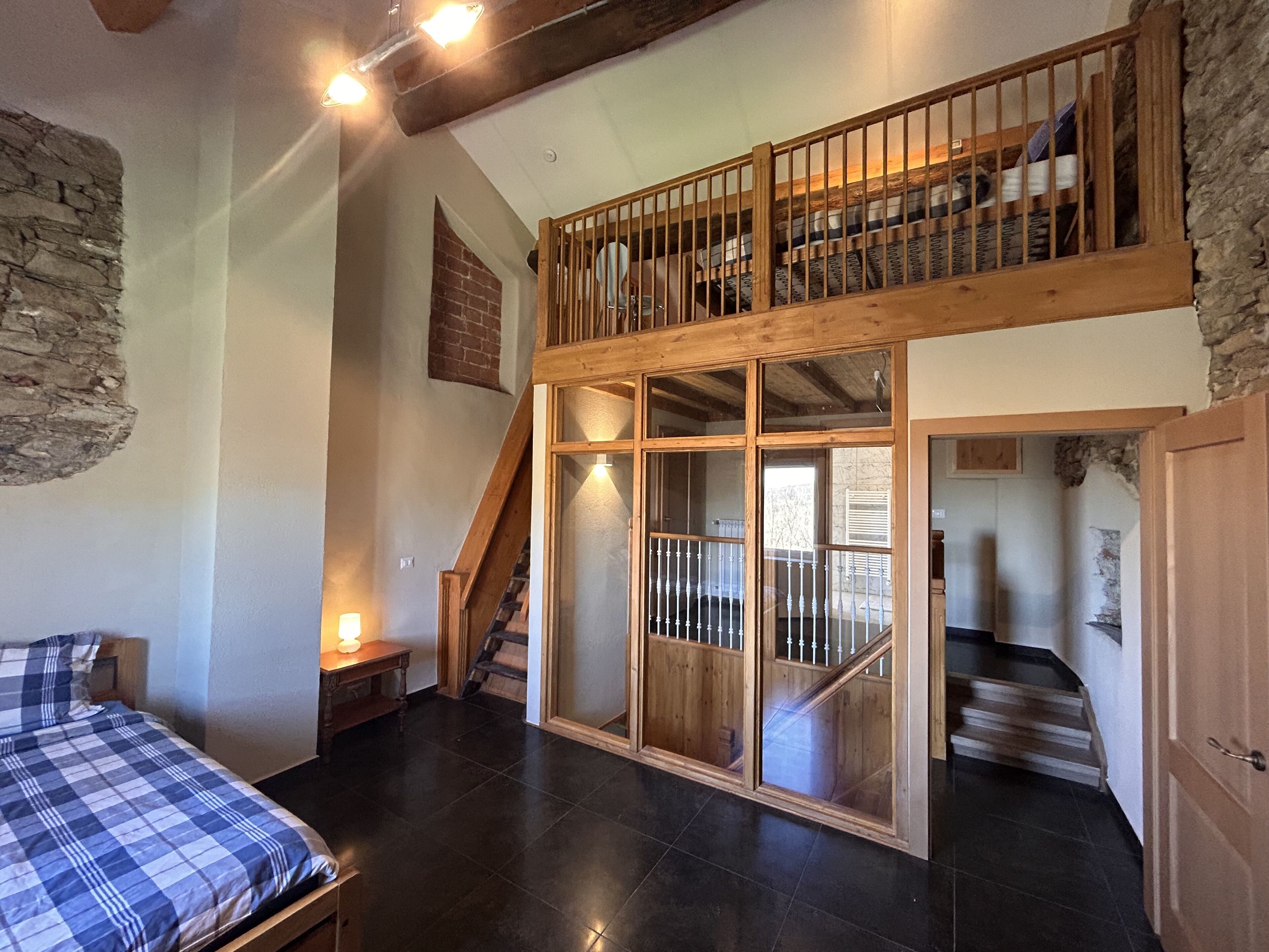 Ein Zimmer mit einem Bett, einer Holztreppe und einem erhöhten Bereich mit Geländer.