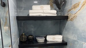 A bathroom with three black shelves holding towels and a decorative item. - Loera’s Inn
Located right off 95 exit Dumfries, 12 minutes from Quantico, VA. (Dumfries)