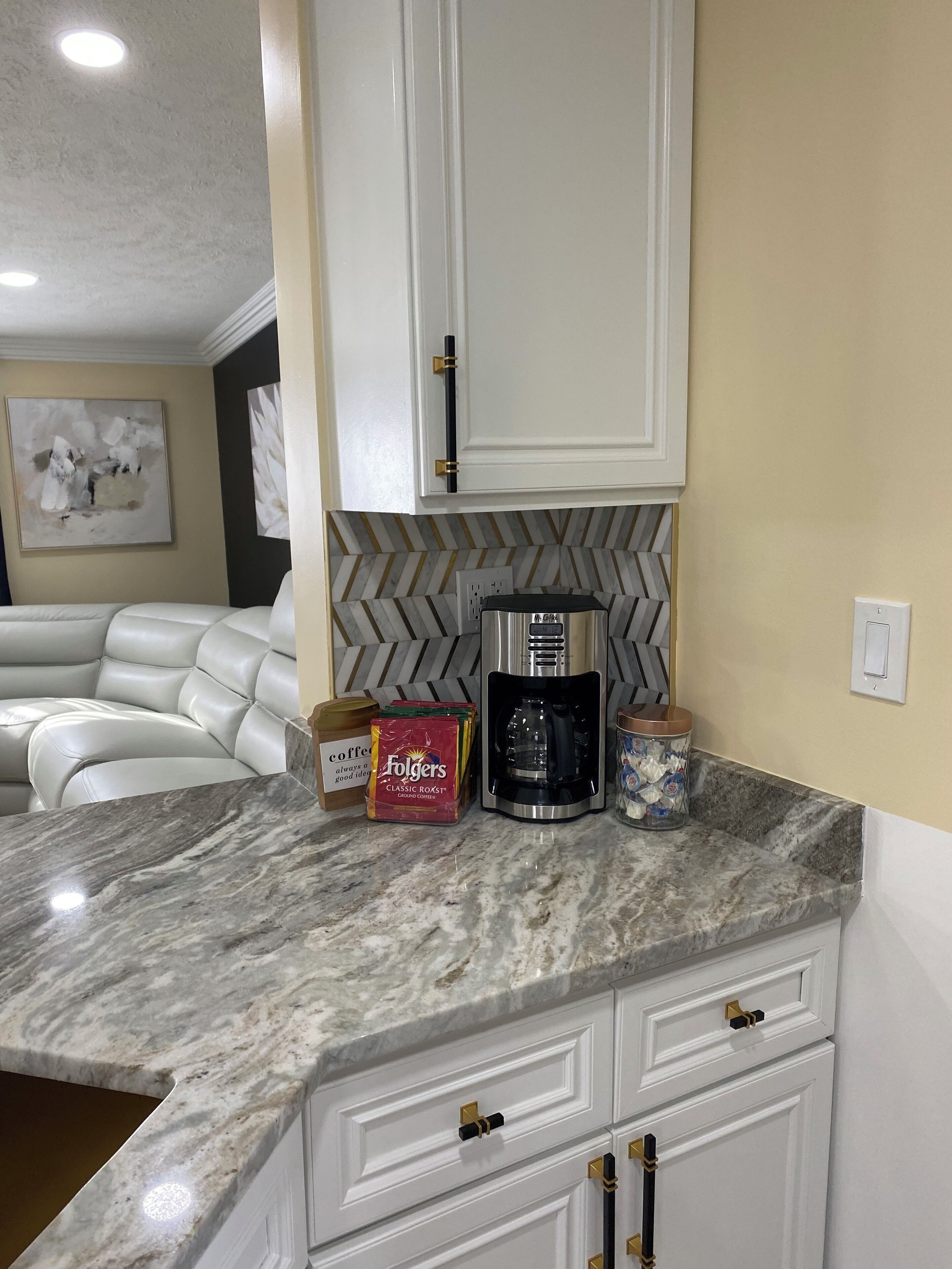 A kitchen with marble countertops, a coffee maker, and coffee pods.