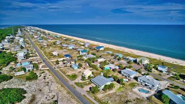 A coastal residential area with houses, a road, and a beach.