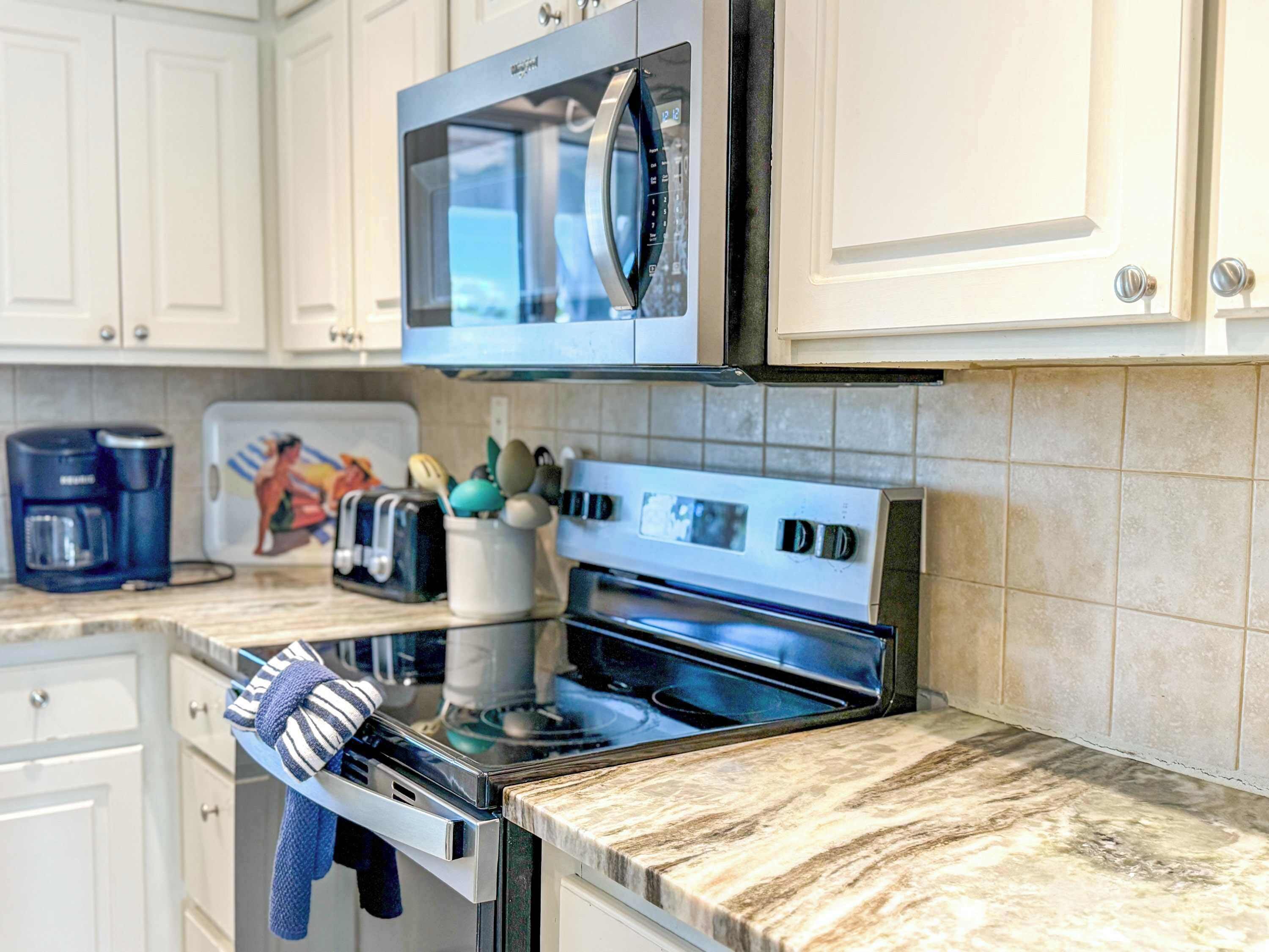 A kitchen with white cabinets, a microwave, a toaster, and a coffee maker.