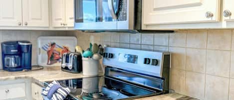 A kitchen with white cabinets, a microwave, a toaster, and a coffee maker.