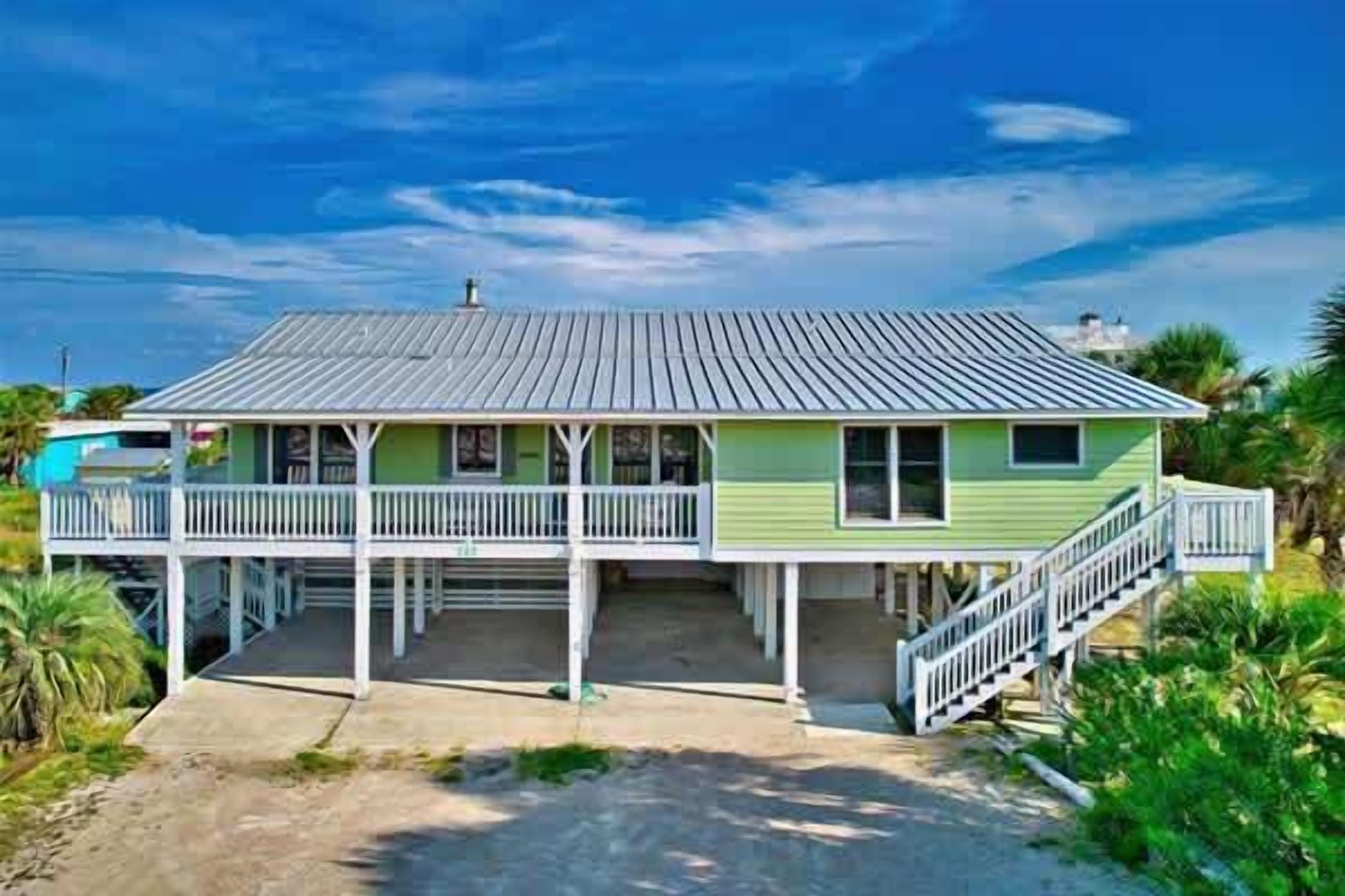 A two-story house with a porch, a staircase, and a view of the ocean.