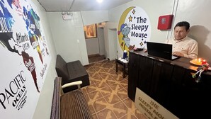 A reception area with a desk, a couch, and a sign for "The Sleepy Mouse Hostel." - The Sleepy Mouse (Cusco)