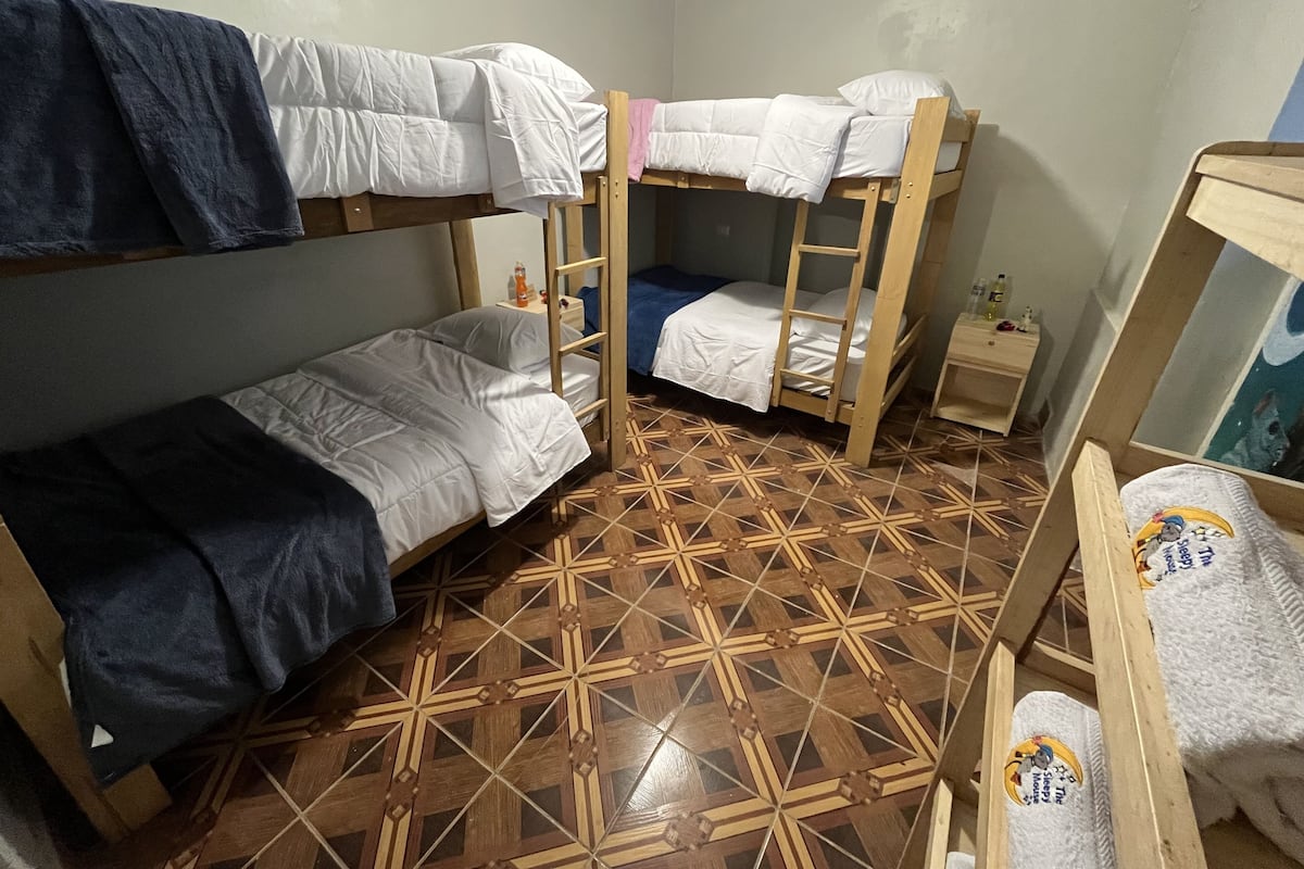 Ein Schlafsaalzimmer mit Etagenbetten, einem kleinen Nachttisch und einem gemusterten Boden.