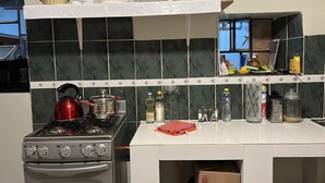 A kitchen with a gas stove, oven, and a microwave. There are shelves with dishes and a basket. - The Sleepy Mouse (Cusco)