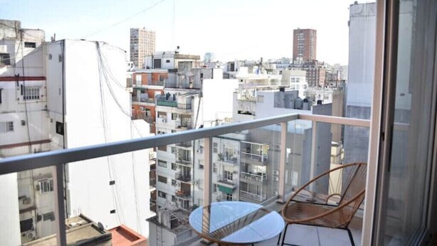 Varanda com vista para uma área urbana densamente povoada, com vários edifícios e céu claro.