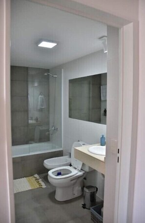Een moderne badkamer met een douchecabine van glas, een toilet en een wastafel.
