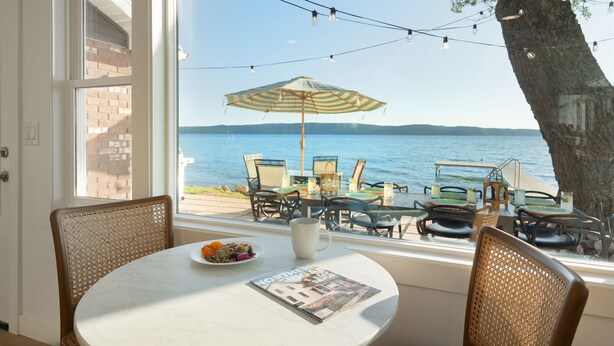 A dining area with a table, chairs, and a view of the lake. - Crystal Lake Retreat with hot tub and dock (Beulah)