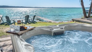 A hot tub with a wooden deck, surrounded by green chairs and a plate of fruit. - Crystal Lake Retreat with hot tub and dock (Beulah)