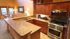 A kitchen with granite countertops, wooden cabinets, a stainless steel range, and a built-in oven. - Ski Bike in out 4 bdrm, 4 bth home w pool table & media room, plus 2 sofa beds (Whistler)