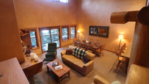 A spacious living room with a large window, a fireplace, a dining area, and a cozy seating arrangement. - Ski Bike in out 4 bdrm, 4 bth home w pool table & media room, plus 2 sofa beds (Whistler)
