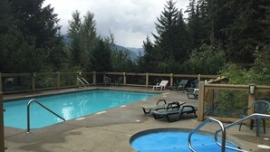 A swimming pool with a small hot tub, surrounded by lounge chairs and a wooden deck. - Ski Bike in out 4 bdrm, 4 bth home w pool table & media room, plus 2 sofa beds (Whistler)