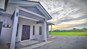 A modern house with a dark front door, a covered porch, and a gravel driveway. - Paddy Villea Inn (Bukit Mertajam)