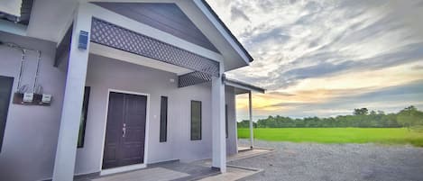 A modern house with a dark front door, a covered porch, and a gravel driveway.